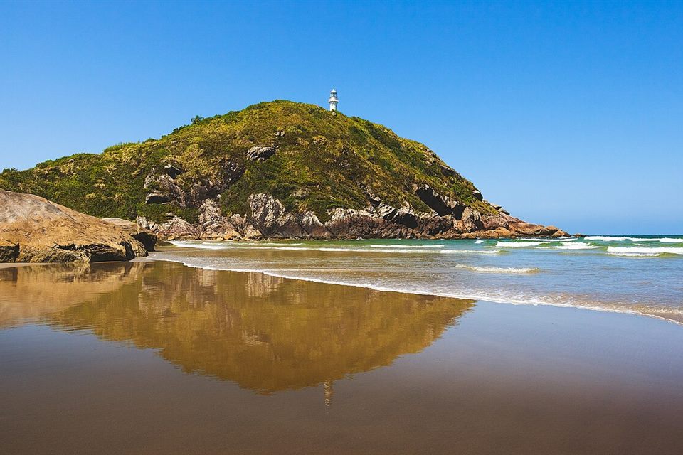Morro do farol refletido na água, na Ilha do Mel